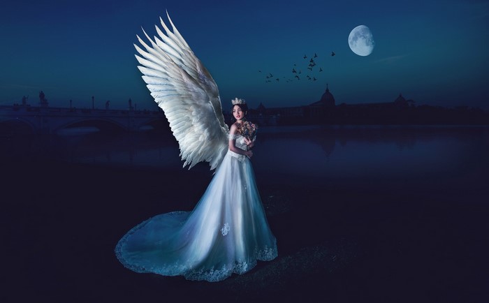 Angel in a white dress with wings at night