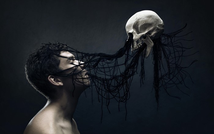 Man entangled with black threads and a skull