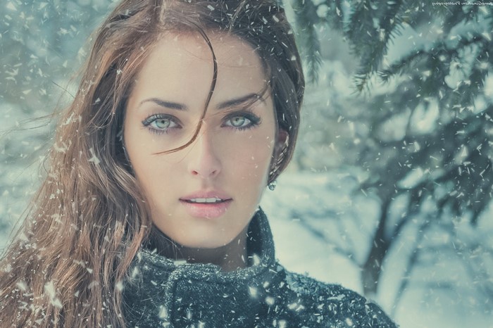 Woman with green eyes in falling snow