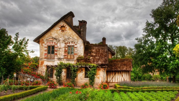 Old French house with garden and cloudy sky