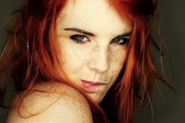 Woman with red hair and green eyes covered in glitter