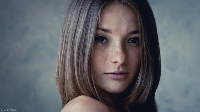 Woman with freckles and straight brown hair looking at viewer