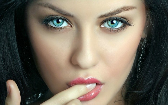 Woman with blue eyes and finger in mouth