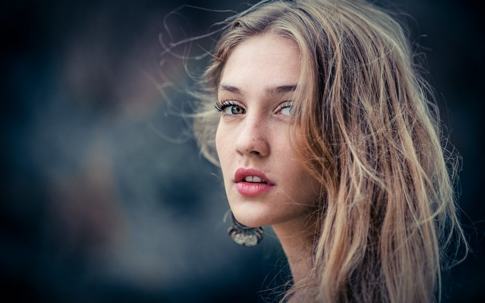 Woman with blonde wavy hair and freckles looking to the side
