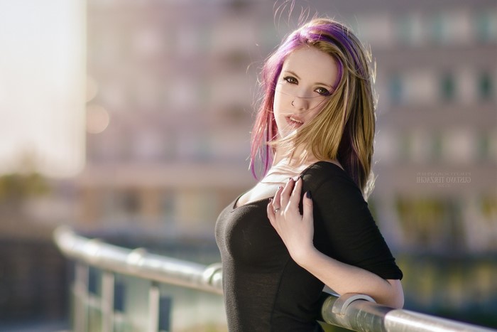 Woman with dyed hair leaning on railing outdoors