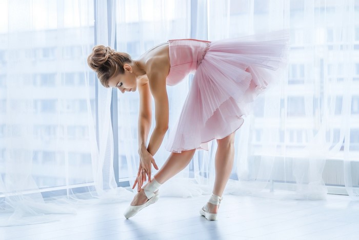 Ballerina in pink tutu stretching on pointe shoes
