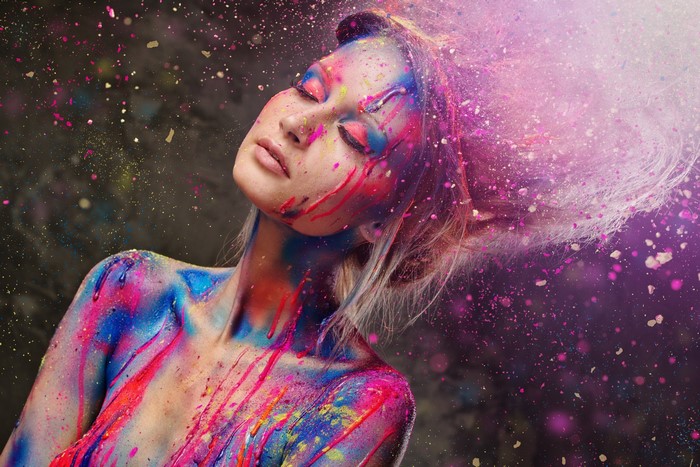 Woman with colorful paint splatter on body and face