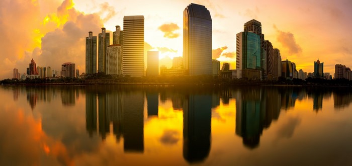 Cityscape with skyscrapers reflecting in water at sunset