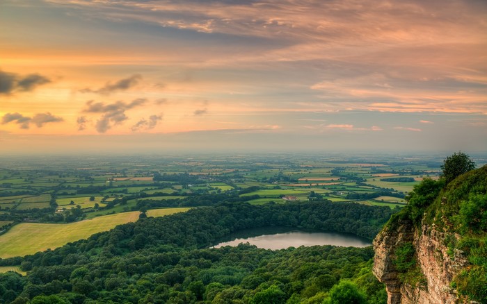 Sunset over a vast landscape with a lake and forest