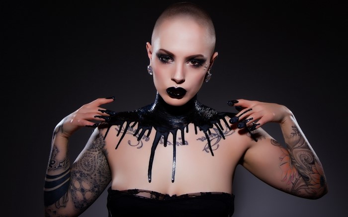 Bald woman with black paint and tattoos