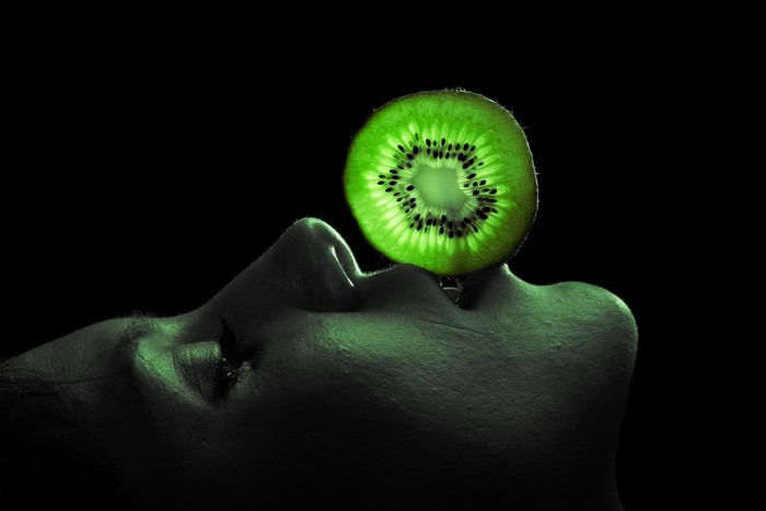 Slice of kiwi fruit on a person's face