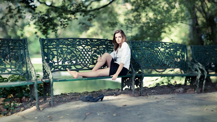Woman sitting on a park bench with shoes off