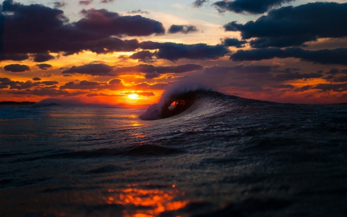 Sunset over ocean with breaking wave
