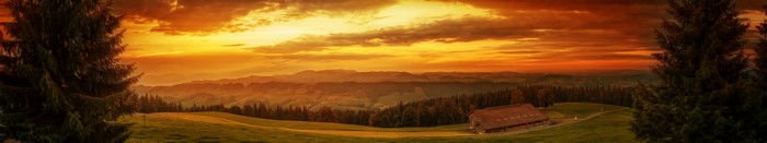 Sunset over rolling hills with a house and trees