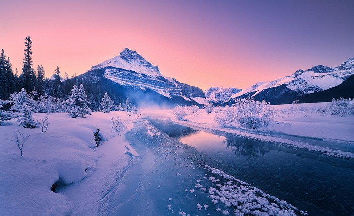 Winter sunrise over snowy mountains and river in Banff National Park