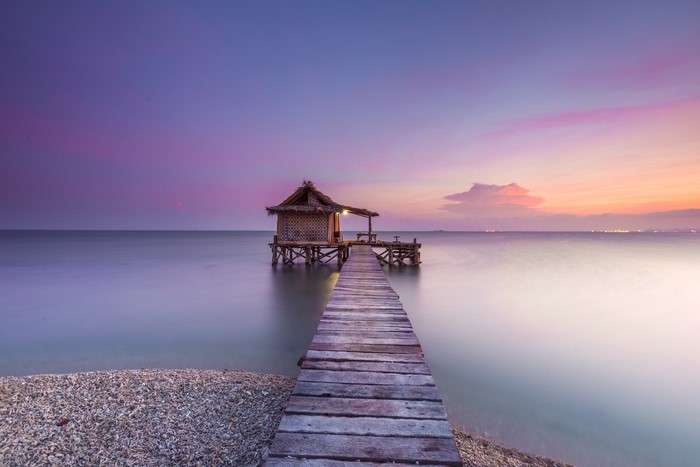 Seaside Wooden Pier Leading to a Small House at Sunset