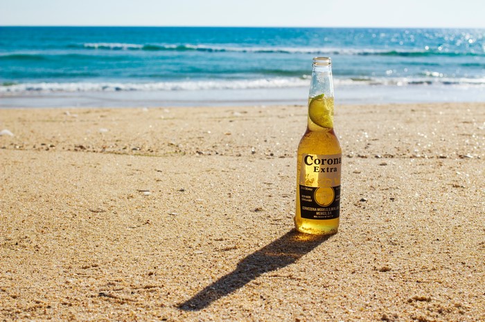 Corona Extra beer bottle with lime on a sandy beach