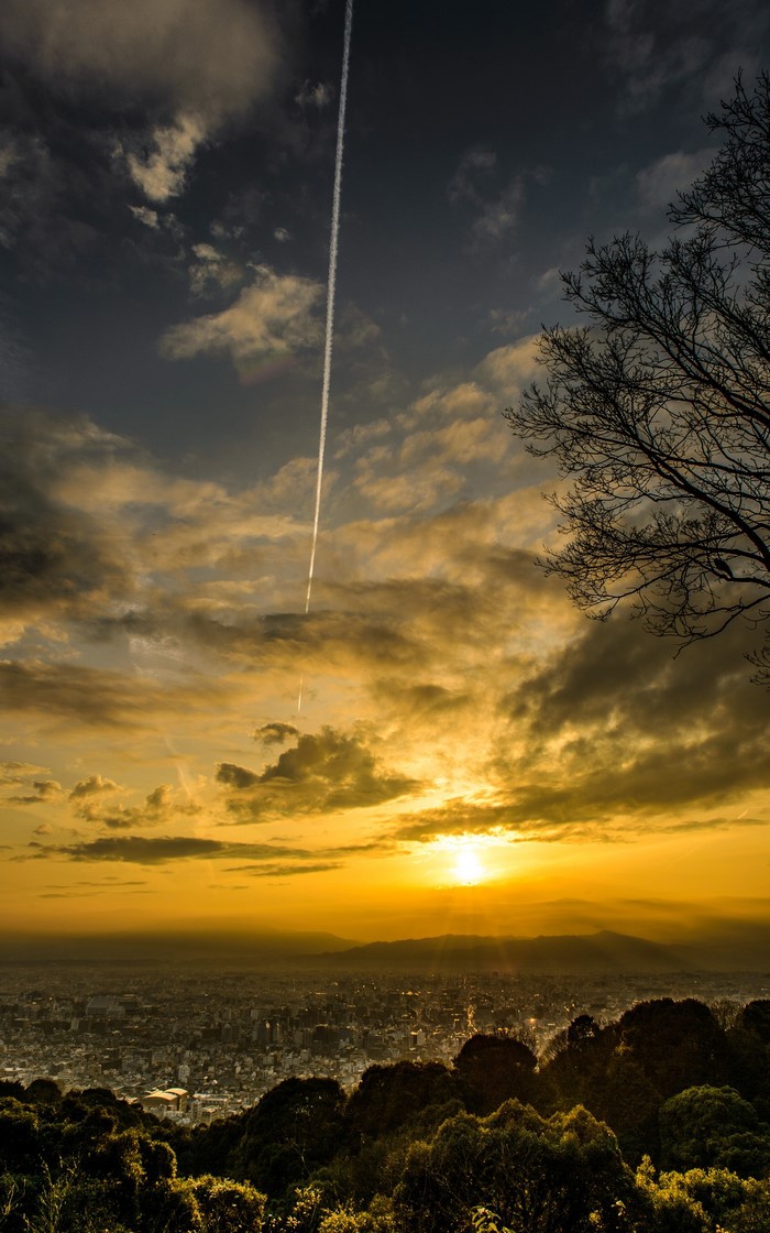 Sunset over a city with a contrail in the sky