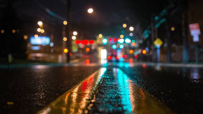 Wet street at night with blurred city lights reflection