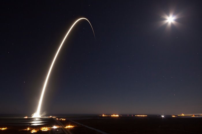 SpaceX rocket launch with moon and stars