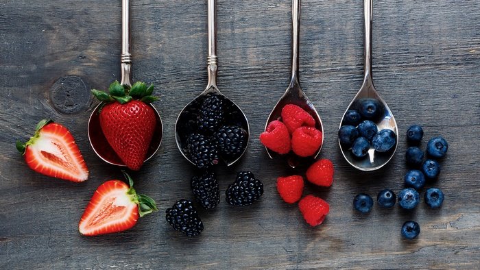 Spoons filled with strawberries, blackberries, raspberries, and blueberries