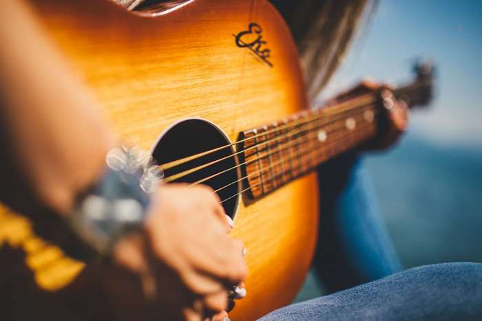 Woman playing acoustic guitar outdoors