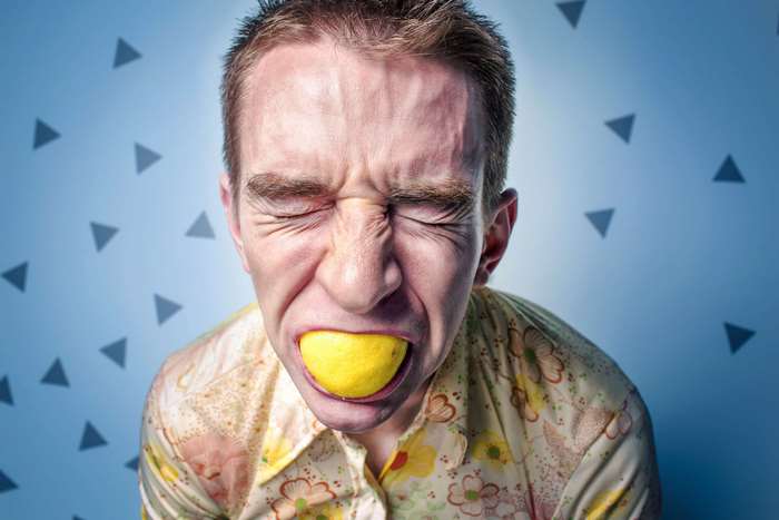 Man making a sour face with a lemon in his mouth 4K