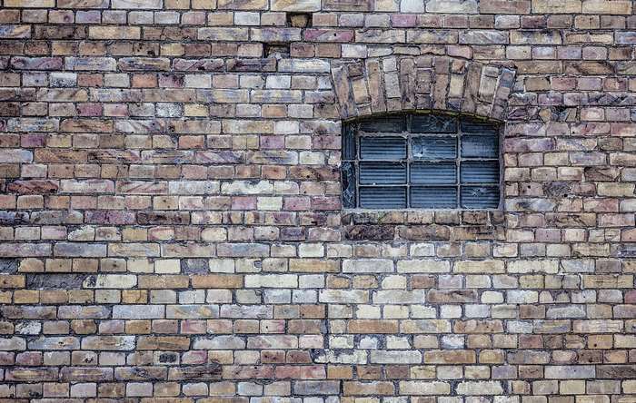Old brick wall with a small arched window