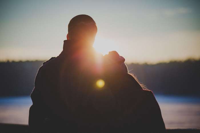 Couple embracing at sunset with lens flare