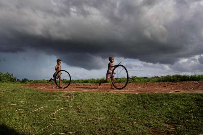 Children Playing with Hoops Under Dramatic Sky in Bangladesh
