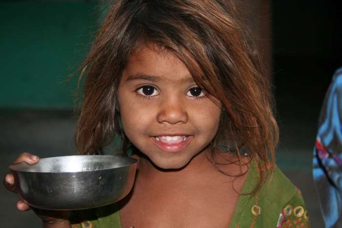 A young girl holding a metal bowl
