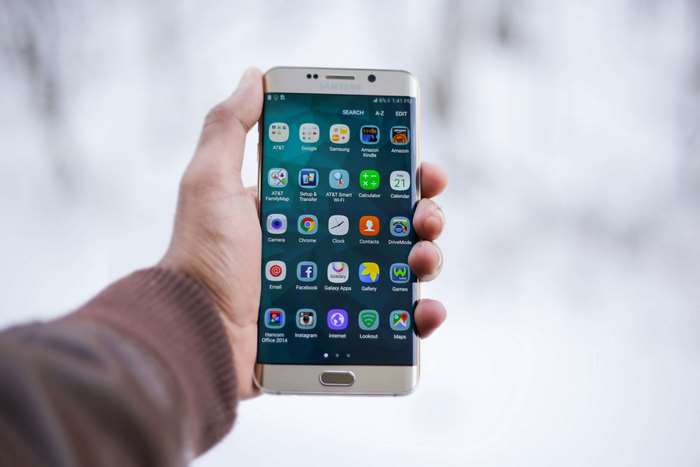 Hand holding Samsung Galaxy S6 Edge Plus with apps