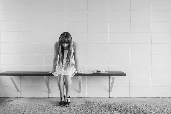 Sad woman sitting on a bench with a newspaper