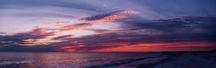Sunset over the ocean with colorful clouds and beach