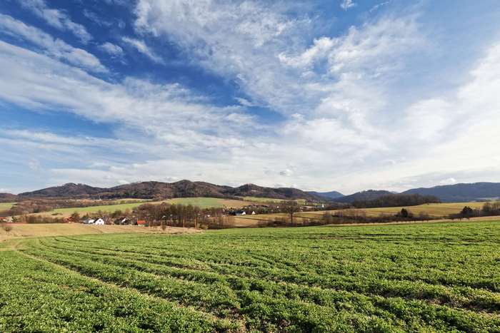 Green fields and mountains under a cloudy sky