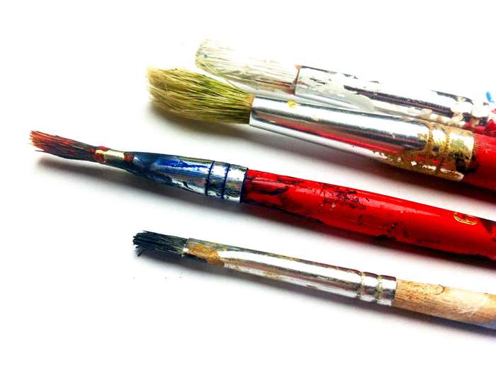 Close-up of used paint brushes with red handles