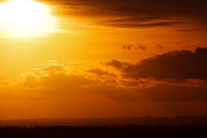 Orange sunset sky with clouds over landscape