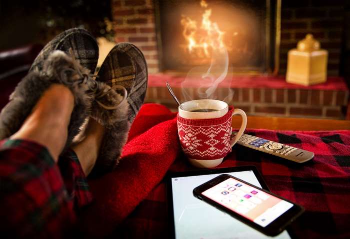 Cozy scene with person relaxing by fireplace with coffee and devices