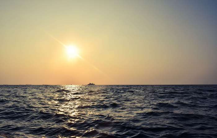 Sunset over the ocean with a distant ship