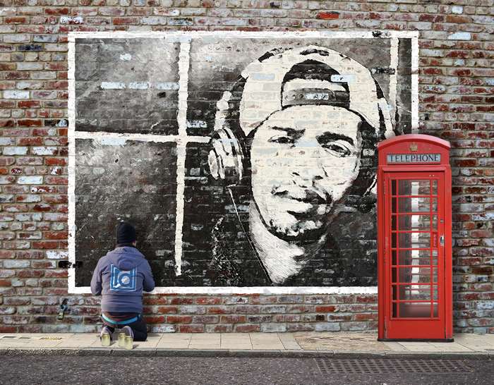 Street art of a man with headphones next to a red telephone box