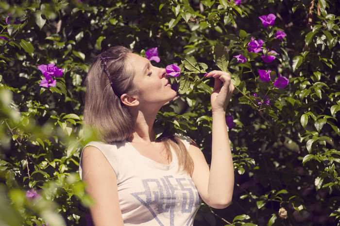 Woman smelling purple flowers in a garden