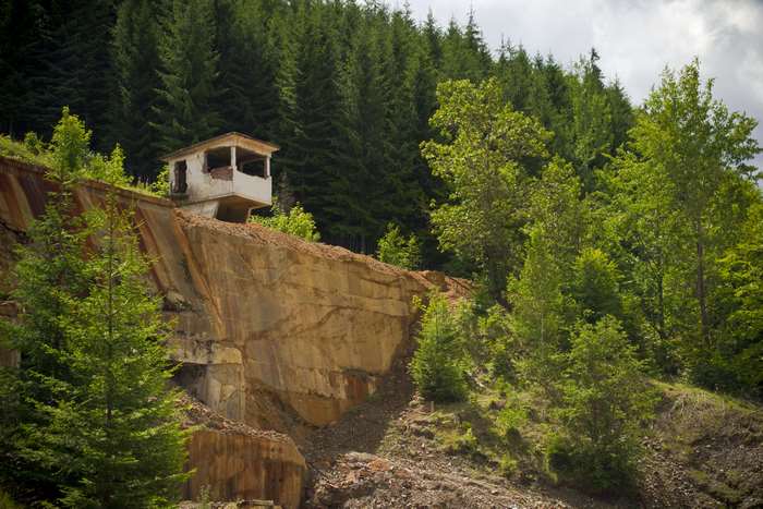 Abandoned structure on a rocky cliffside with forest