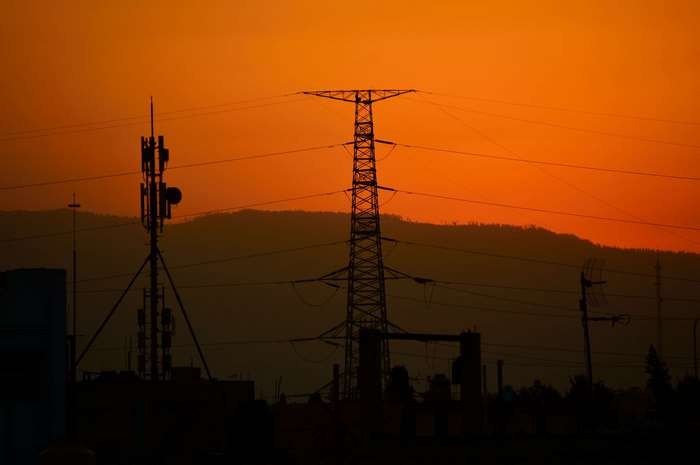 Silhouette of power lines and cell towers at sunset
