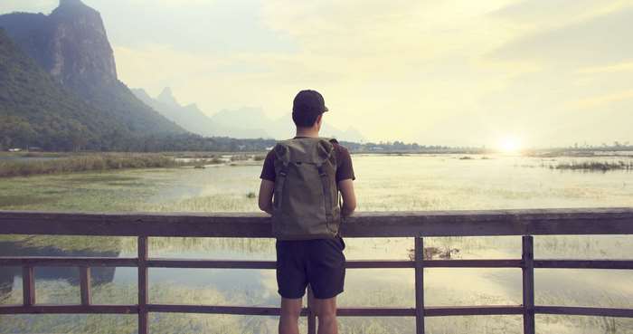 Backpacker looking at a mountain lake at sunset