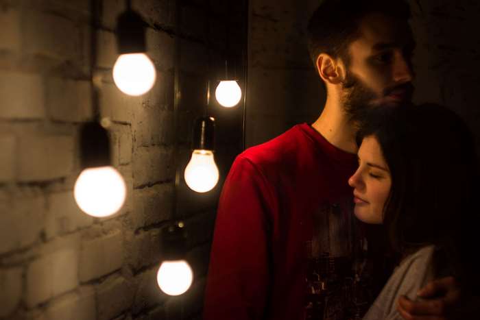 Couple embracing near hanging light bulbs