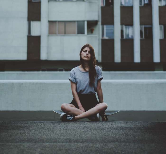 Woman sitting on a skateboard in front of a building