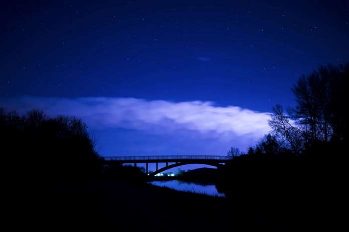 Bridge over river at night with starry sky
