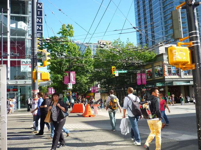 People walking on a busy city street with traffic lights