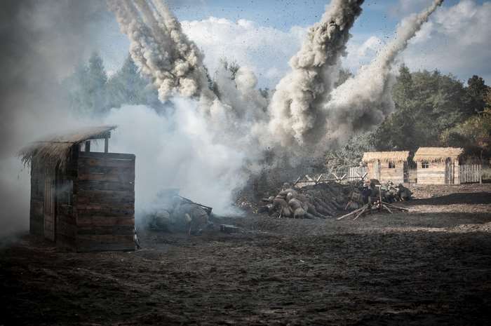Explosion and smoke over a battlefield with wooden structures
