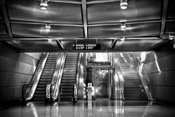 Modern airport interior with escalators, elevator, and stairs
